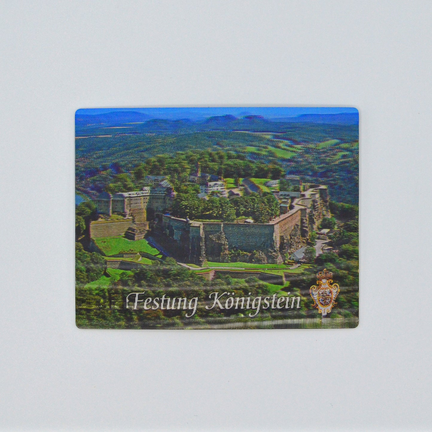 in 3 D, Luftaufnahme Festung Königstein im Elbsandsteingebirge, blauer Himmel, unten weiße Schrift geschwungen: Festung Königstein und Wappen Augusts