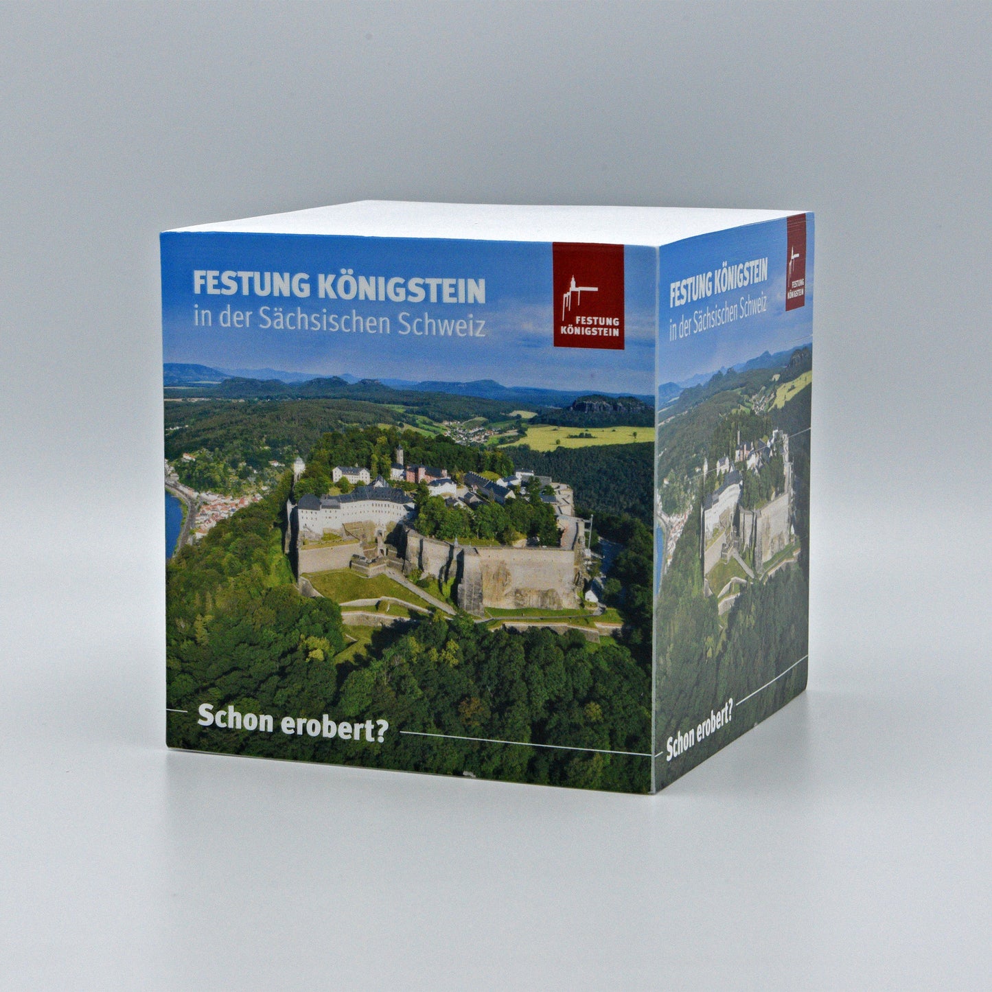 Notizblock, Luftaufnahme der Festung Königstein mit Elbsandsteingebirge auf den Außenseiten, blauer Himmel, weiße Schrift: Festung Königstein in der sächsischen Schweiz daneben Logo, unten weiße Schrift: schon erobert?