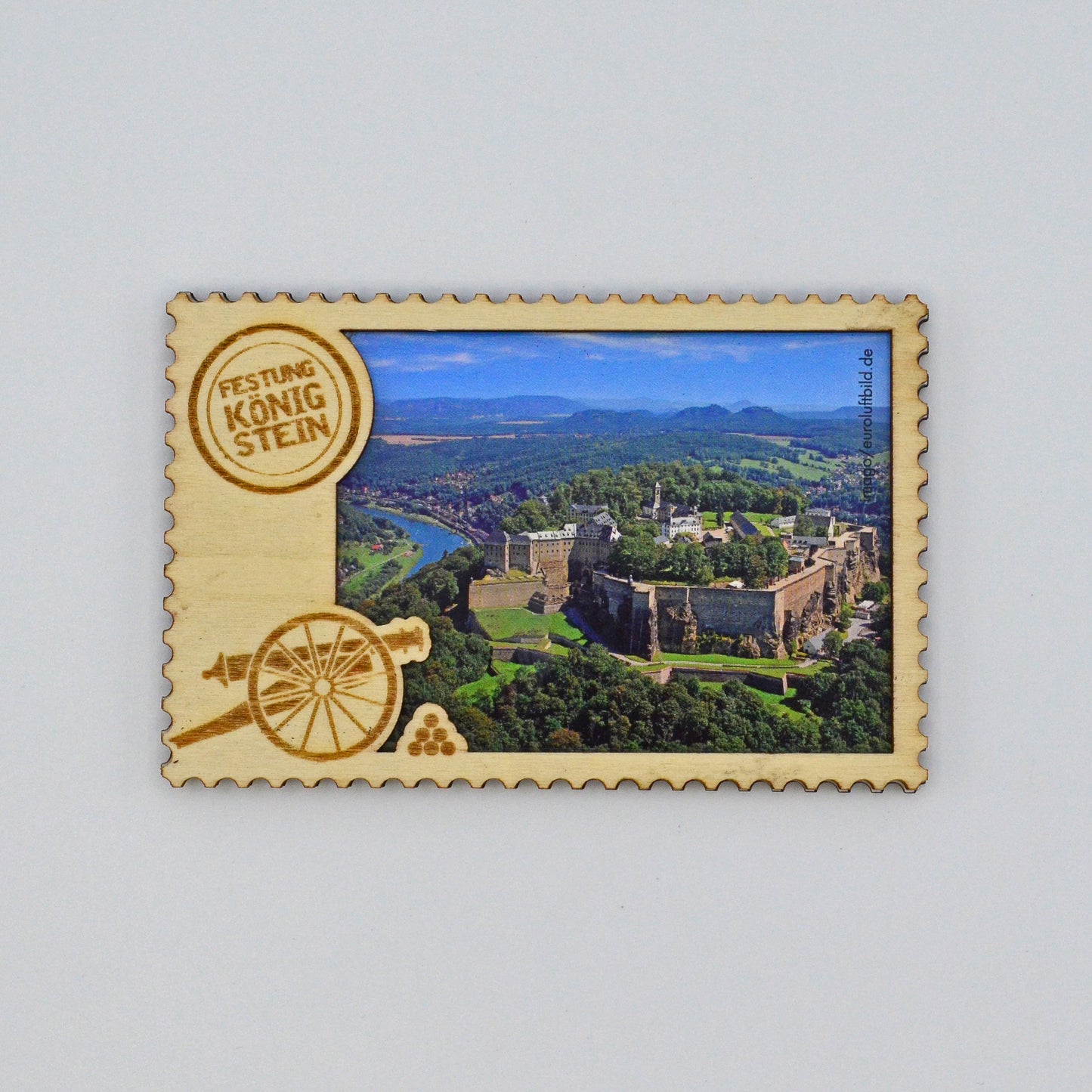 Luftaufnahme Festung Königstein im Elbsandsteingebirge, mit Holzrahmen, links Branding Logo und eine Kanone mit Kugeln