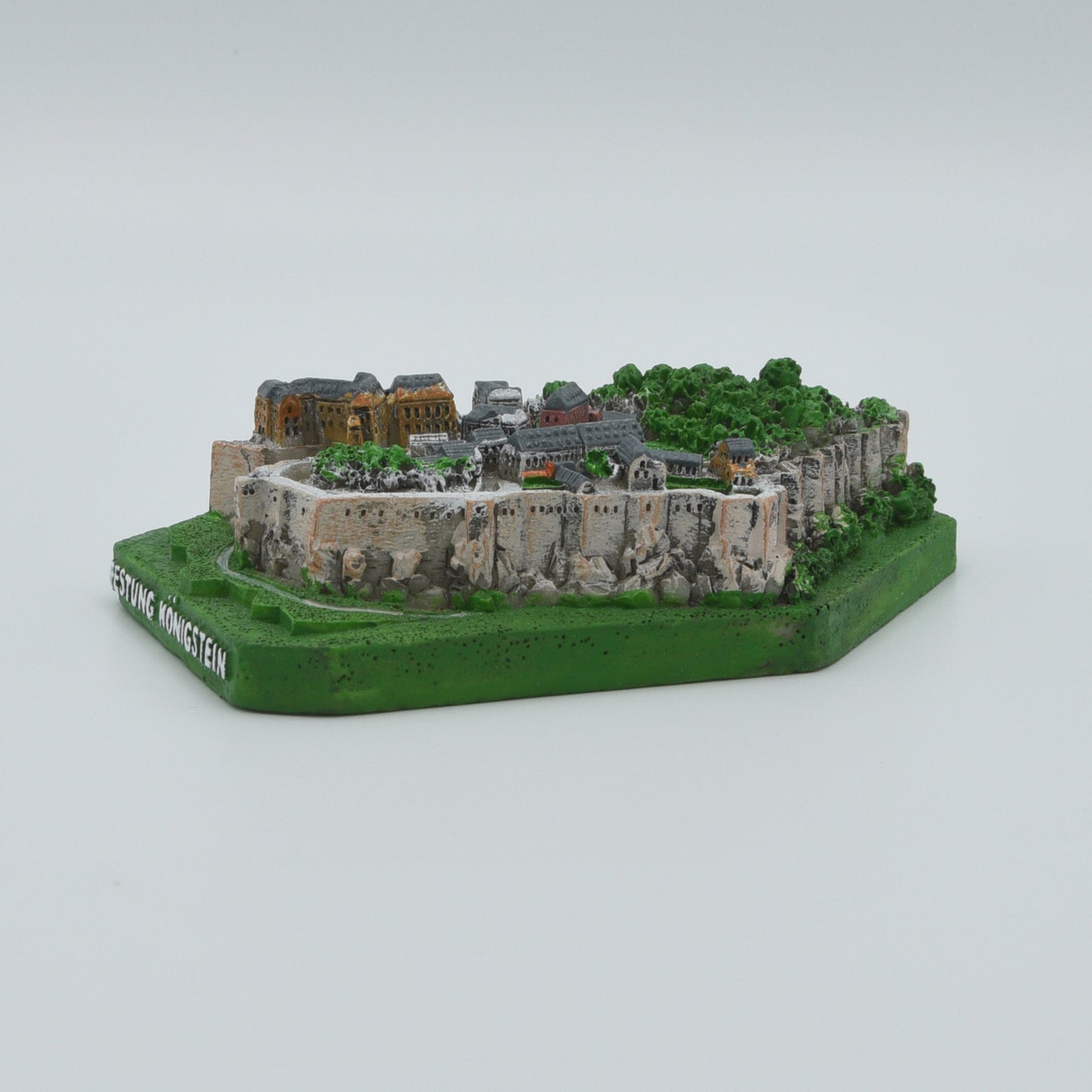 Modell Festung Königstein, grüner Sockel mit weißer Schrift: Festung Königstein, Festung in verschiedenen Grau- und Brauntönen, Sicht von rechts des Modells