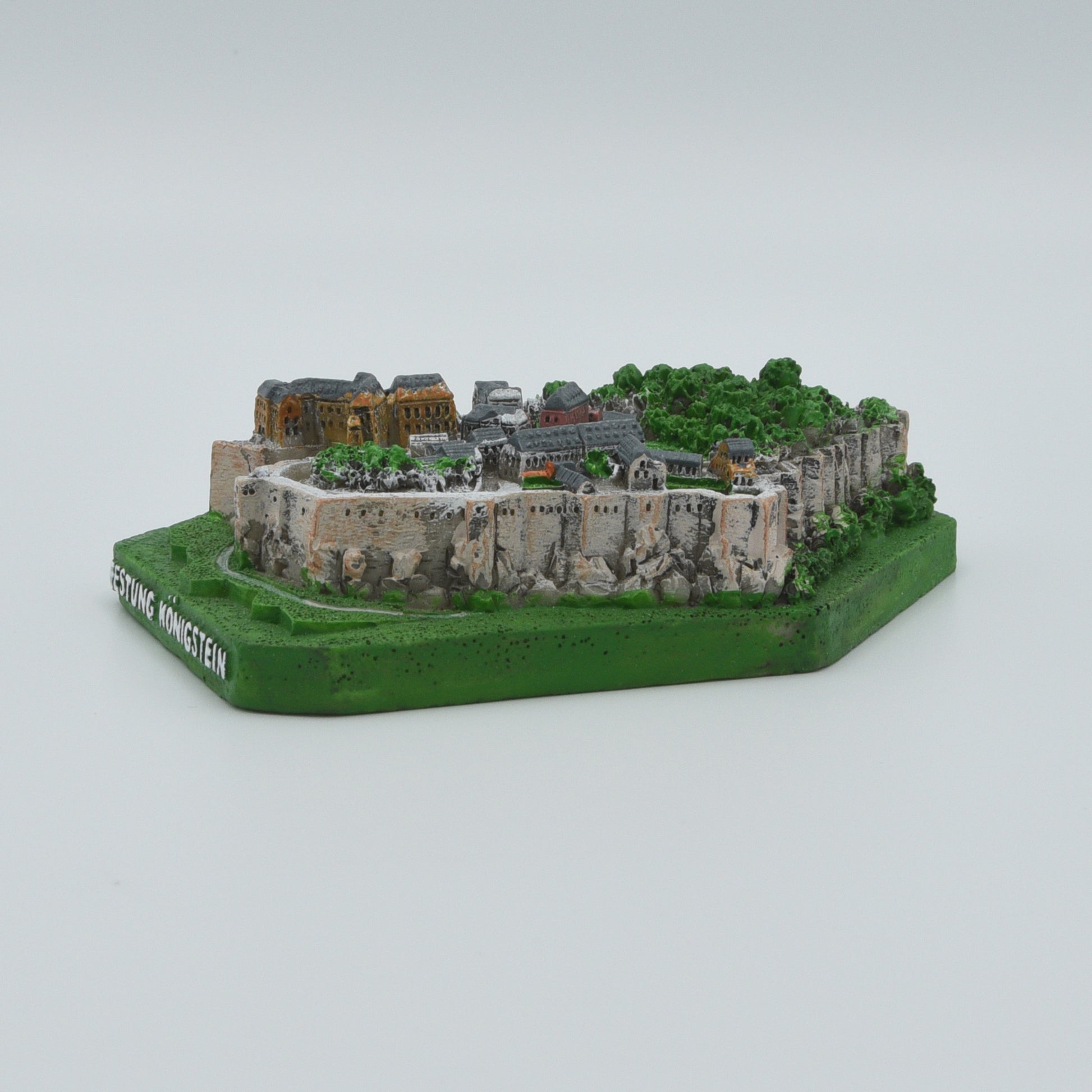 Modell Festung Königstein, grüner Sockel mit weißer Schrift: Festung Königstein, Festung in verschiedenen Grau- und Brauntönen, Sicht von rechts des Modells