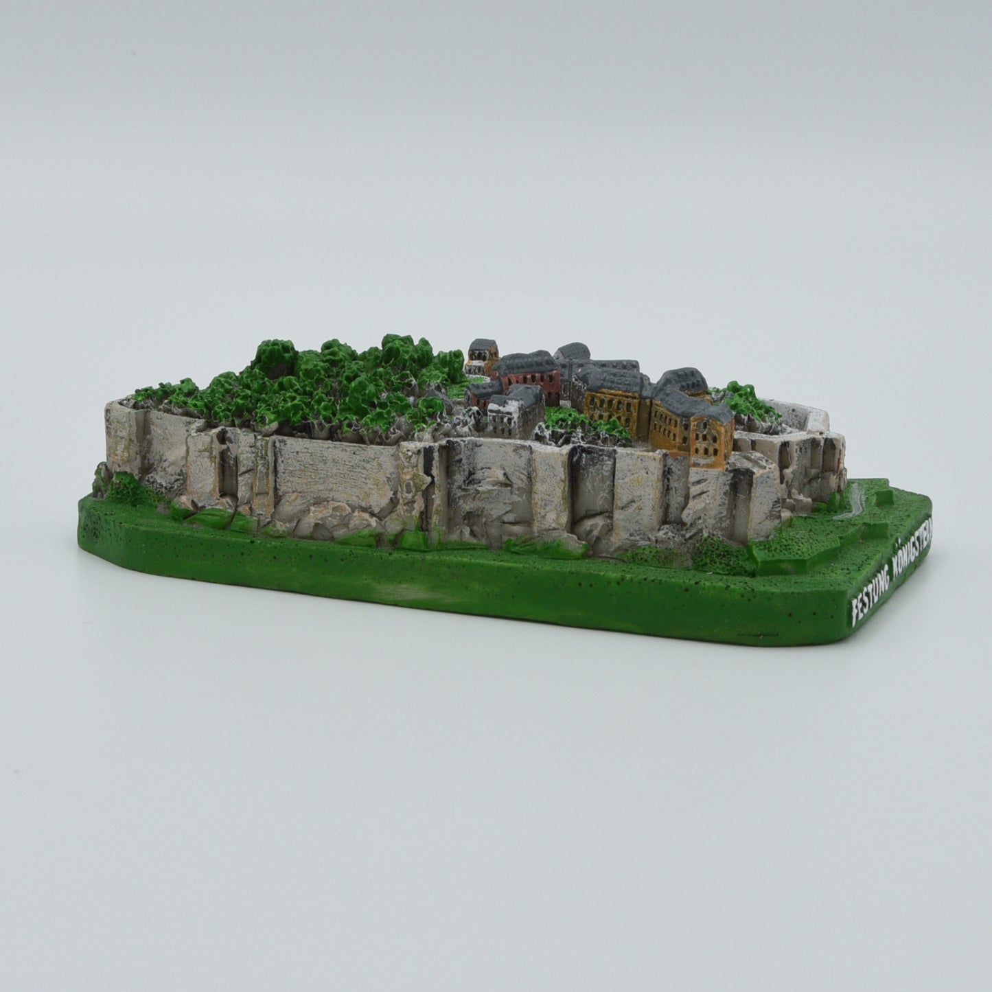Modell Festung Königstein, grüner Sockel mit weißer Schrift: Festung Königstein, Festung in verschiedenen Grau- und Brauntönen, Sicht von links des Modells