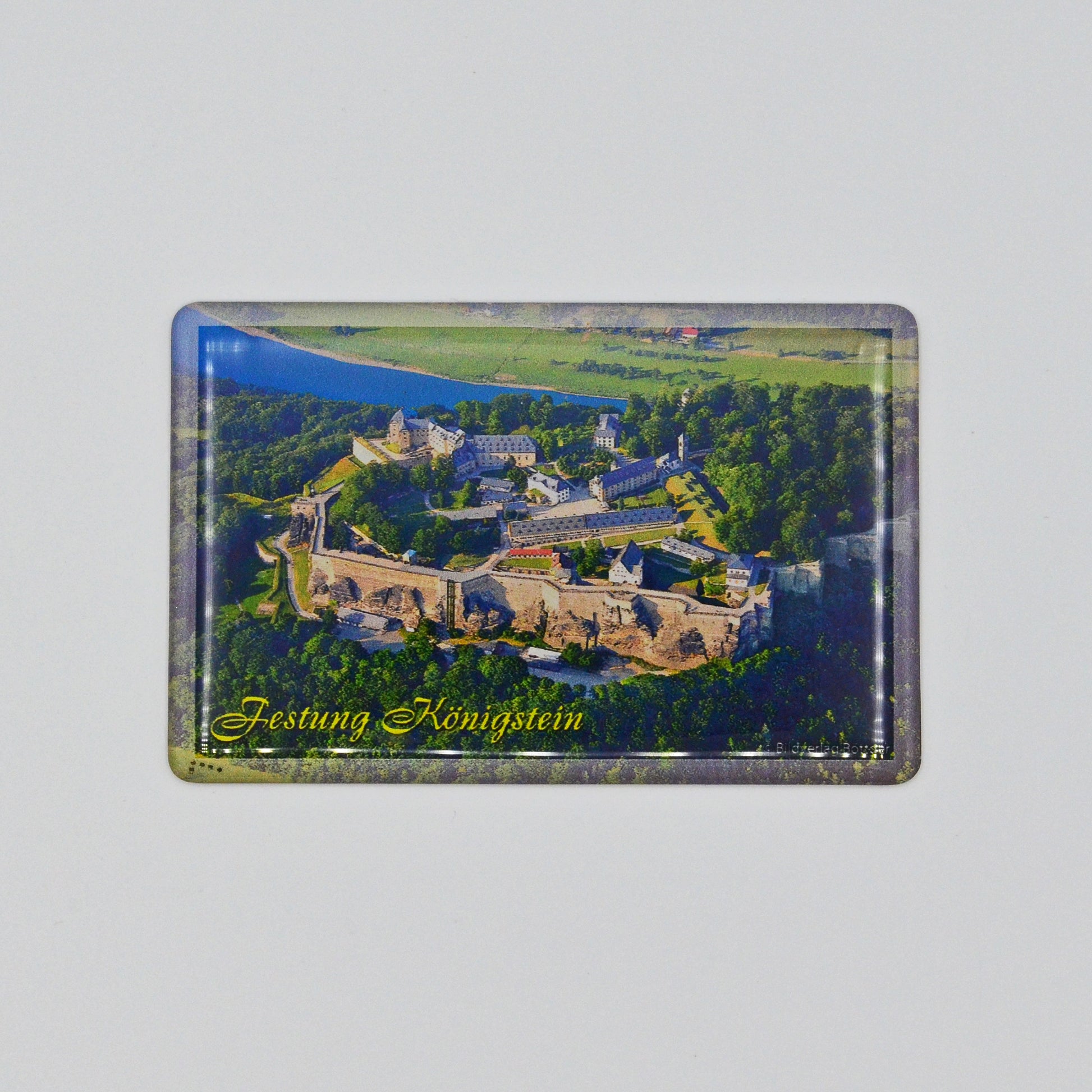 Luftaufnahme Festung Königstein, im Hintergrund die Elbe, geschwungene gelbe Schrift unten links: Festung Königstein