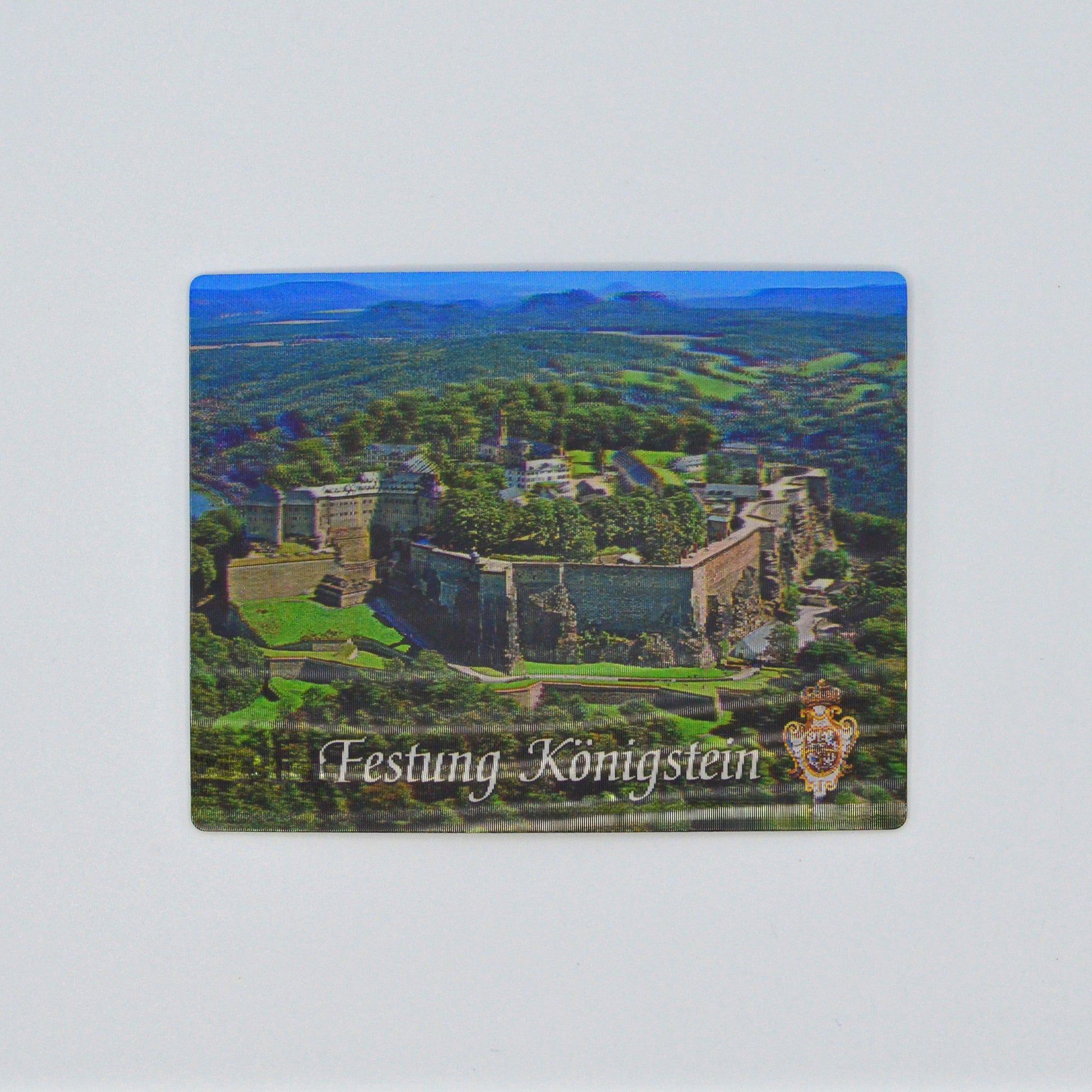 in 3 D, Luftaufnahme Festung Königstein im Elbsandsteingebirge, blauer Himmel, unten weiße Schrift geschwungen: Festung Königstein und Wappen Augusts