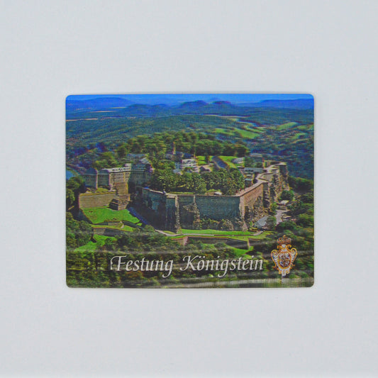 in 3 D, Luftaufnahme Festung Königstein im Elbsandsteingebirge, blauer Himmel, unten weiße Schrift geschwungen: Festung Königstein und Wappen Augusts