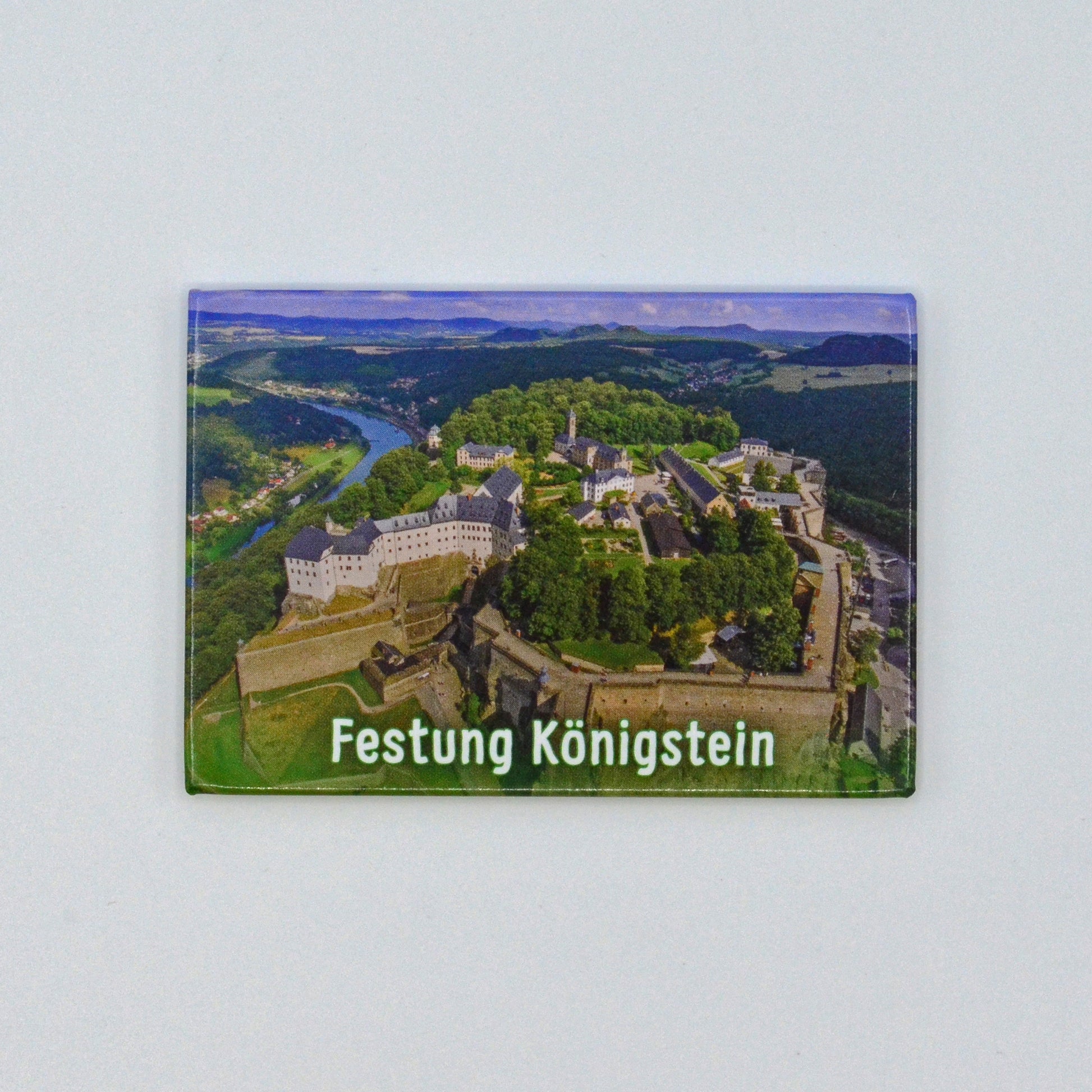 Luftaufnahme Festung Königstein von Westen im Elbsandsteingebirge, blauer Himmel, weiße Schrift unten mittig: Festung Königstein