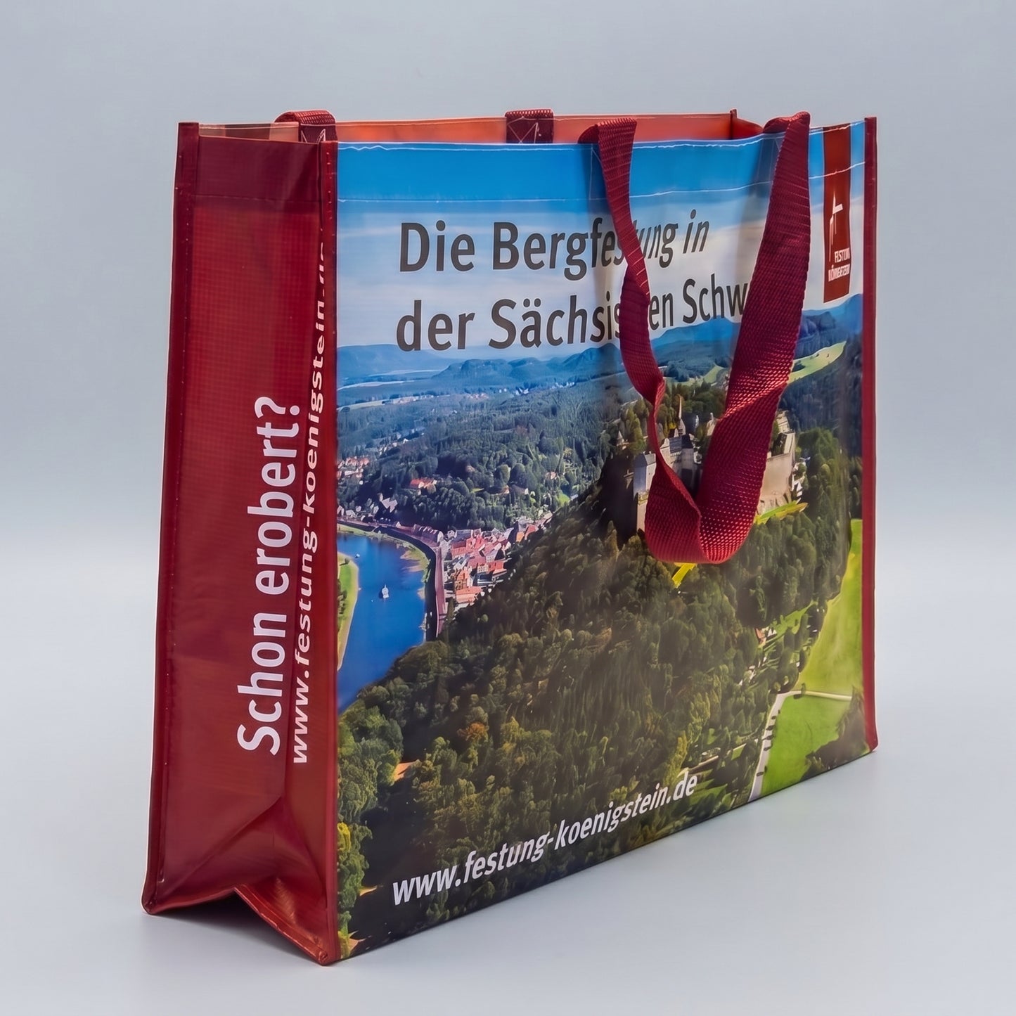 Mehrwegtasche, rote Umsäumung und Henkel, Luftbild der Festung Königstein mit Elbsandsteingebirge vorn, weiße Schrift auf roter Seite: Schon erobert? mit Internetadresse