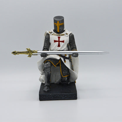 Ritter, anthrazit-silberner Rüstung, darüber weißes Templer-Hemd mit Umhang, kniet auf Sockel und präsentiert ein  Schwert (Kugelschreiber) in silber mit goldenem Griff, Sicht von vorn
