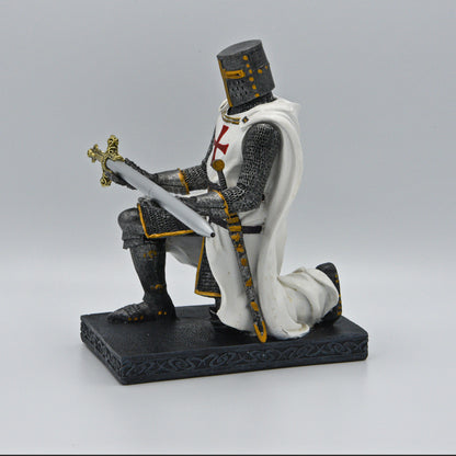Ritter, anthrazit-silberner Rüstung, darüber weißes Templer-Hemd mit Umhang, Schwert an Hüfte, kniet auf Sockel und präsentiert ein  Schwert (Kugelschreiber) in silber mit goldenem Griff, Sicht von rechts
