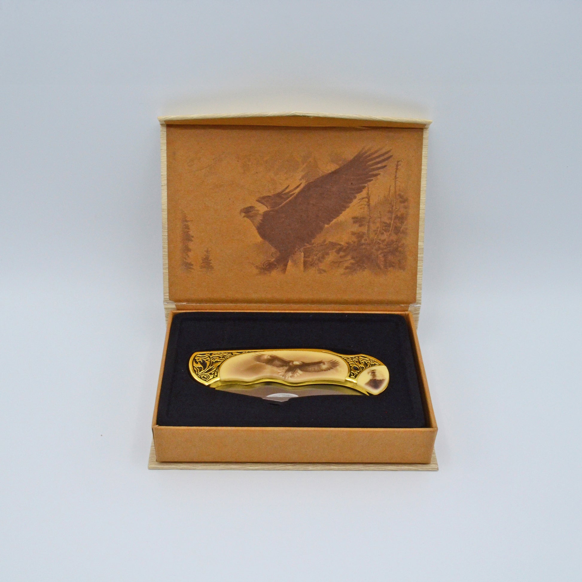 geöffnete helle Geschenkbox mit Adler im Deckel, darin Klappmesser, heller Griff mit Adler und Verzierungen