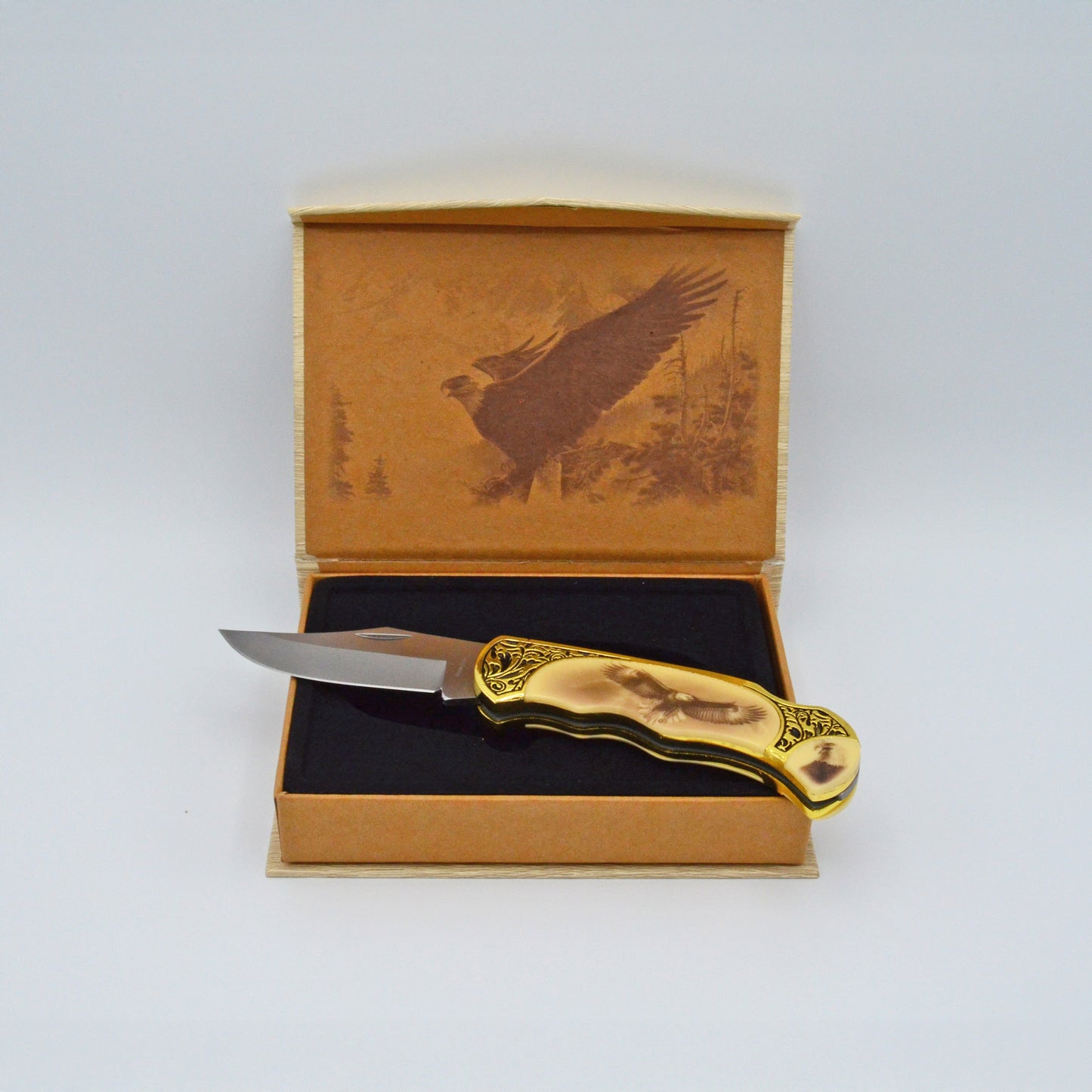 geöffnete helle Geschenkbox mit Adler im Deckel, darauf Klappmesser, heller Griff mit Adler und Verzierungen, aufgeklappt