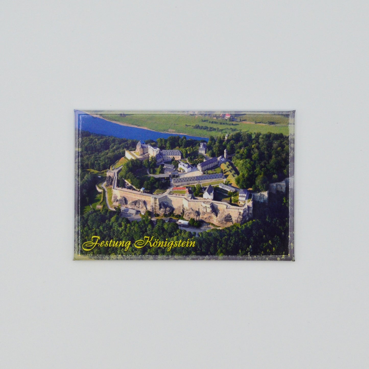 Luftaufnahme Festung Königstein, im Hintergrund die Elbe, geschwungene gelbe Schrift unten links: Festung Königstein