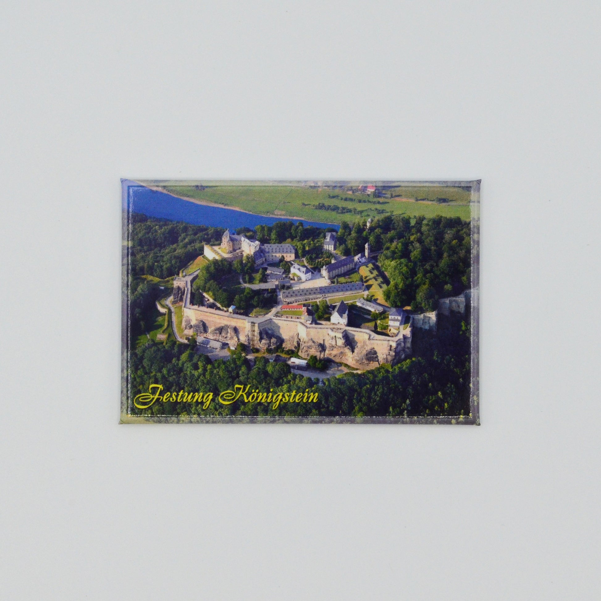 Luftaufnahme Festung Königstein, im Hintergrund die Elbe, geschwungene gelbe Schrift unten links: Festung Königstein
