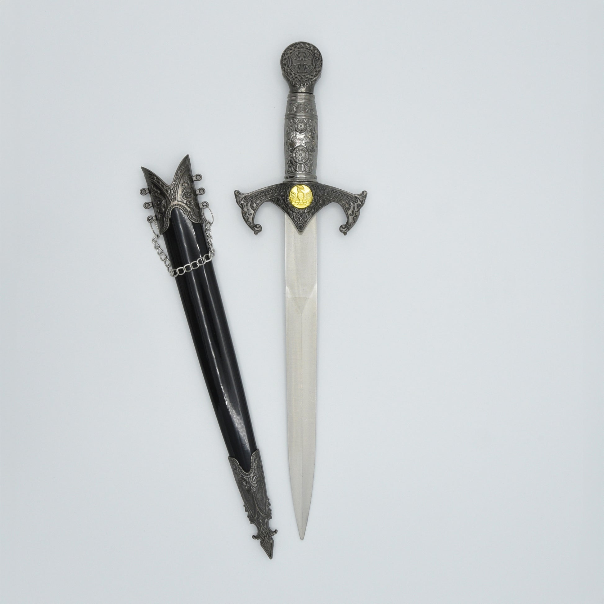 verzierter Dolch mit Kreuzrittersymbolik, daneben zugehörige Scheide in schwarz mit Verzierungen und Kettchen am Schaft, ungeschliffene Klinge ist sichtbar